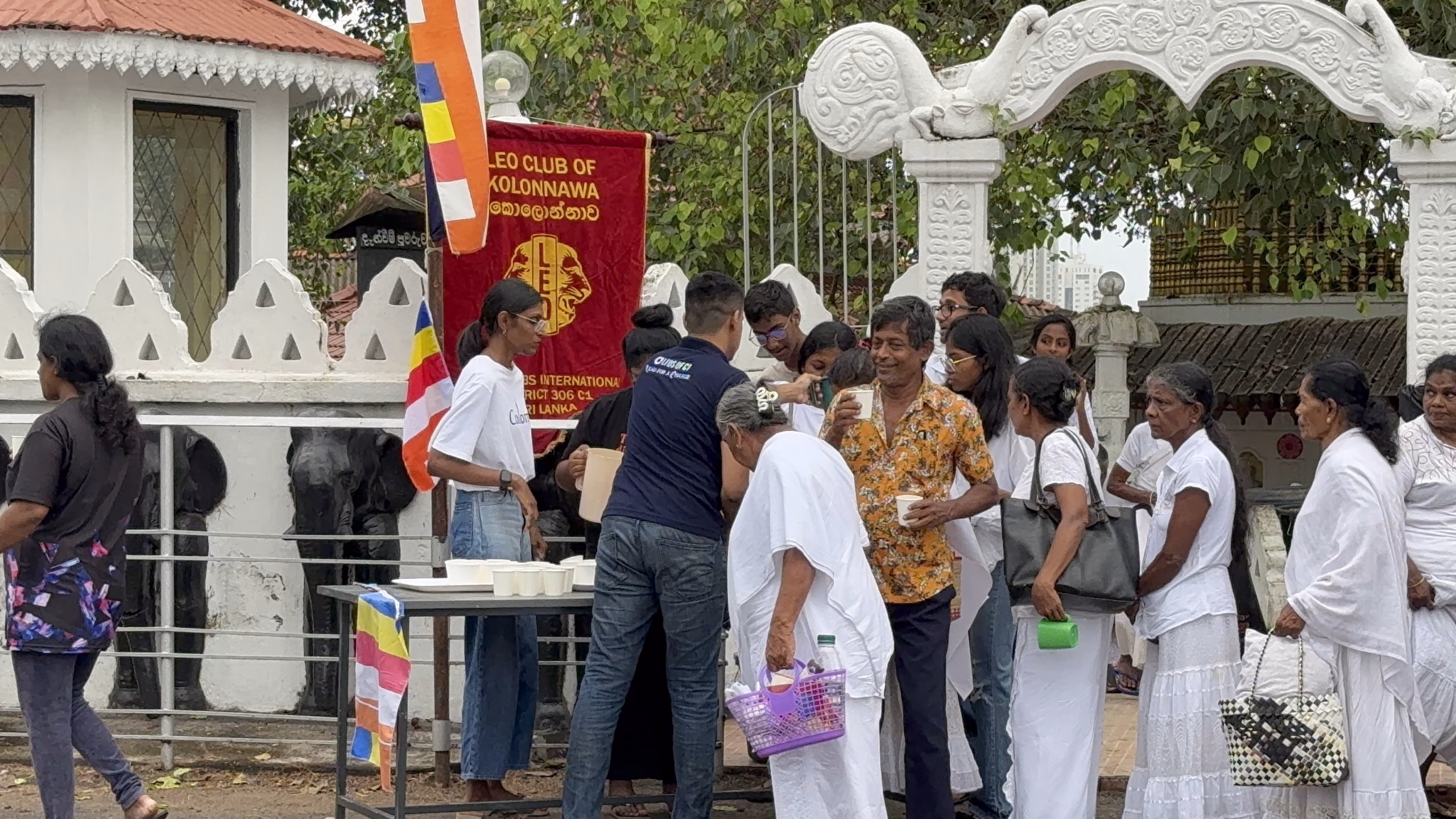 Leo Club of Kolonnawa members serving sisil pan to devotees outside Gothatuwa Sri Gnanawimalaramaya Temple on Poson Poya Day.